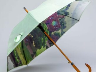 Ljusgrönt paraply med tryck av ett herrgårdslandskap på insidan.