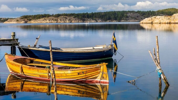 Förtöjda träbåtar i lugnt vatten vid en klippig skärgård