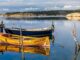Förtöjda träbåtar i lugnt vatten vid en klippig skärgård