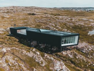 Modern svart byggnad med solpaneler på en karg, stenig ö