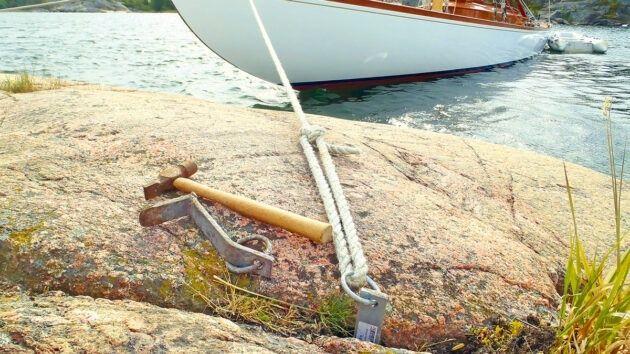 Förtöjningslina och bergkil säkrar en båt vid skärgårdsklippa