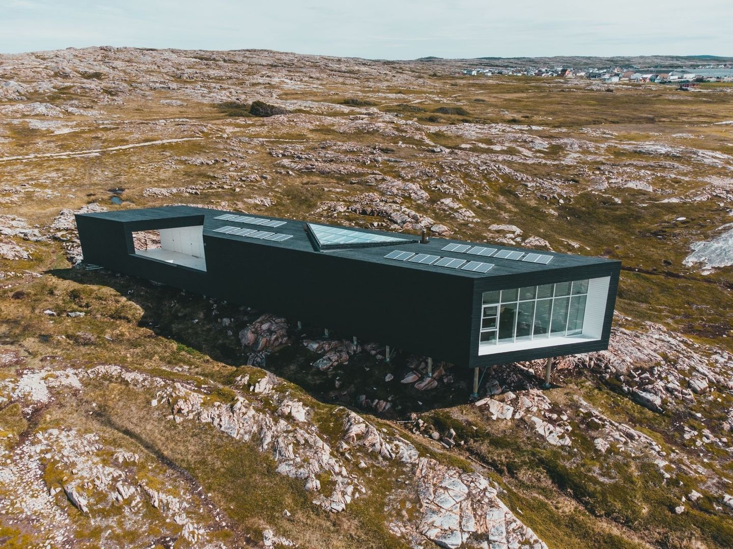 Modern off-grid-hus med solpaneler i ett kargt kustlandskap
